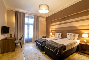A hotel room with a large bed, a desk, a chair, a television, and a window with curtains.