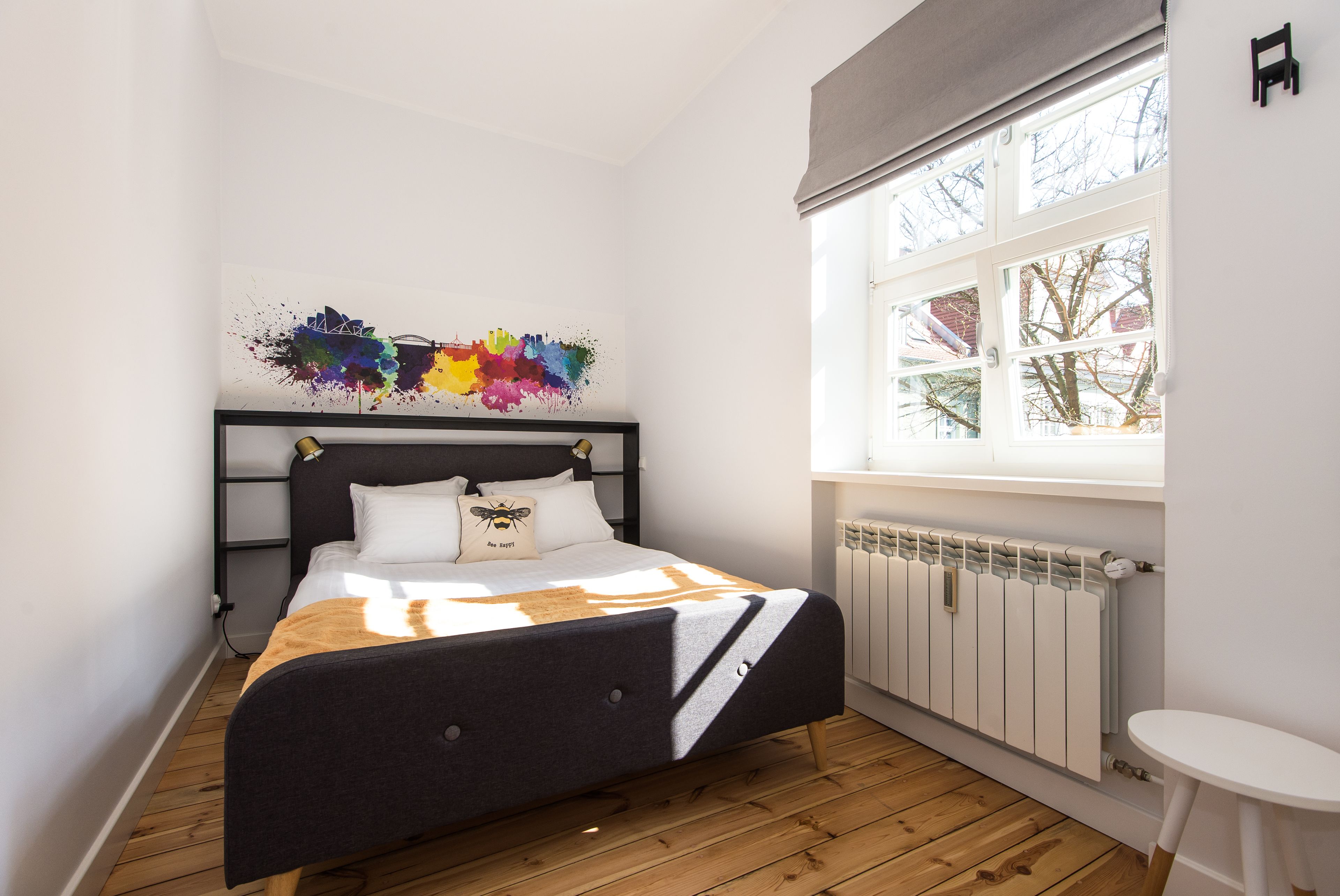 Un dormitorio con una cama, un ventanal y una pequeña mesa.