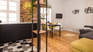 A modern kitchen with a brick wall, a neon sign, and a dining area with a wooden floor. - Bliss Apartments Sydney (Poznan)