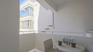 Un balcon avec une table et des chaises, une bouteille d’eau et une tasse.