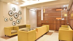 Un hall con sofás amarillos, una recepción y decoración mural.
