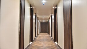Un pasillo largo y estrecho con puertas de madera a ambos lados y un suelo con diseño.