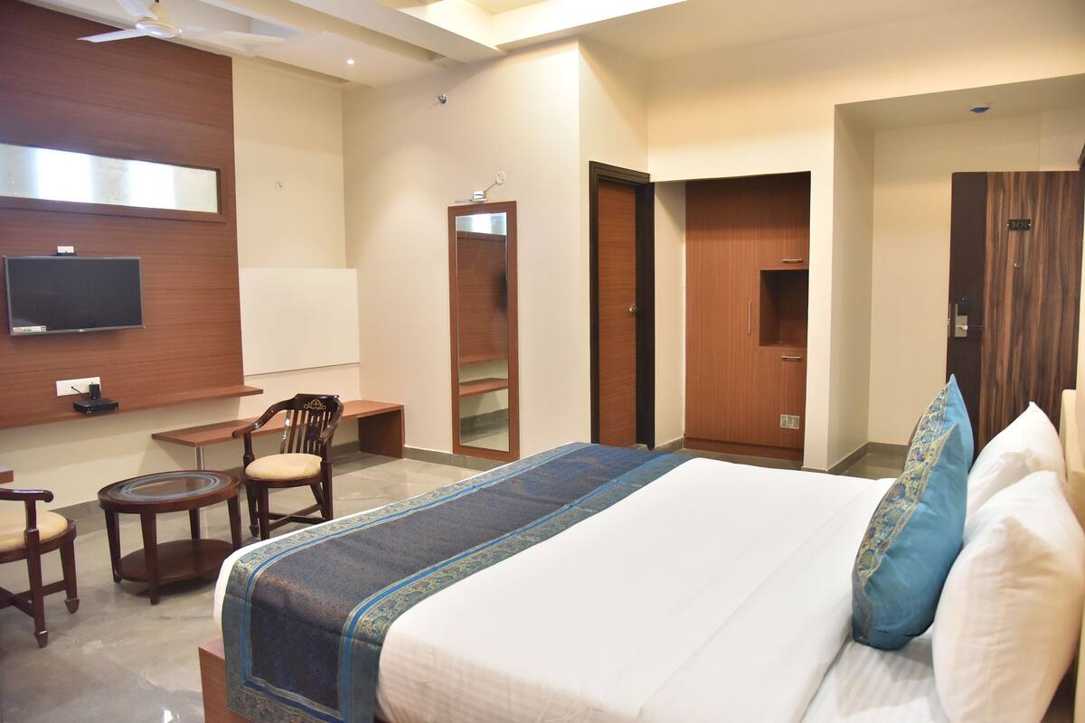 A hotel room with a bed, a TV, a desk, a chair, and a mirror.