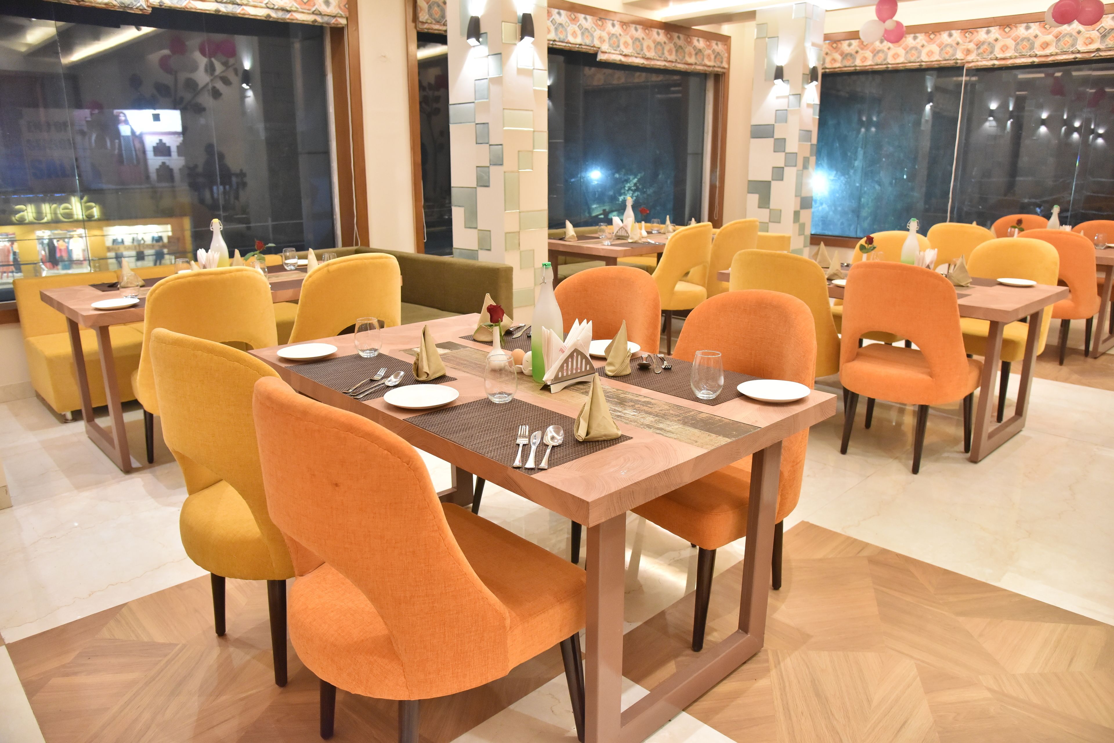 A restaurant with multiple tables and chairs, each set with plates, cutlery, and napkins.