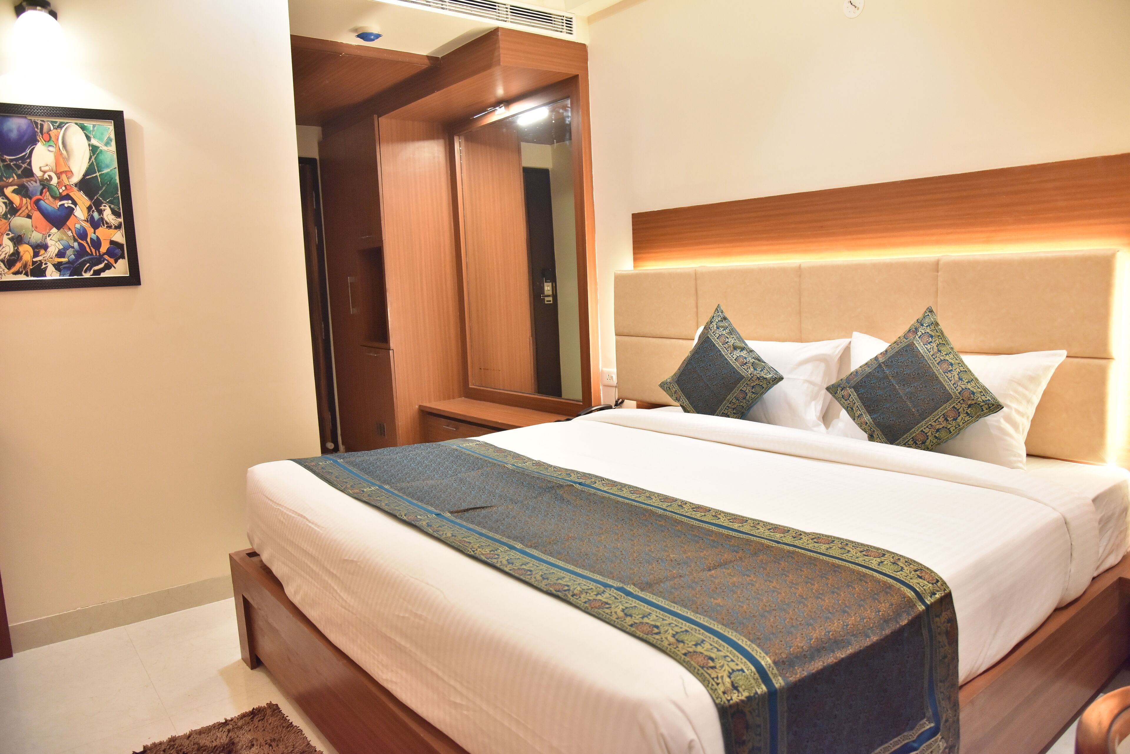A neatly made bed with a patterned bedspread, a wooden headboard, and decorative pillows.