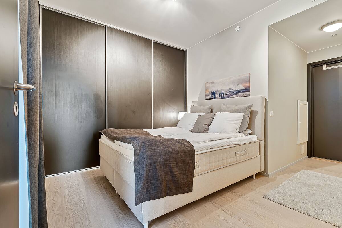 Un dormitorio moderno con cama, un armario grande y un cuadro en la pared.