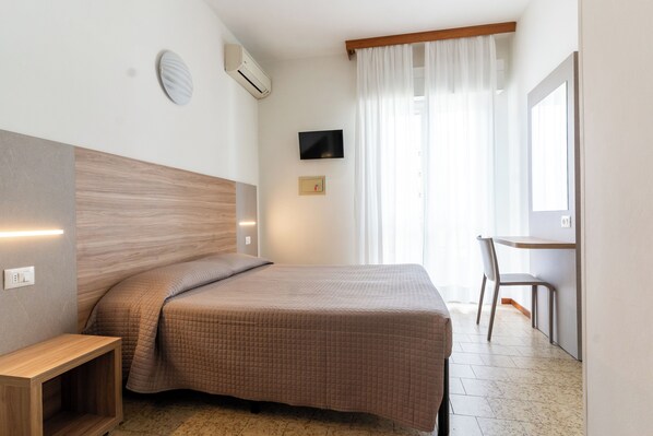 Une chambre à coucher comprenant un lit, une table de chevet, une télévision et un bureau avec une chaise.