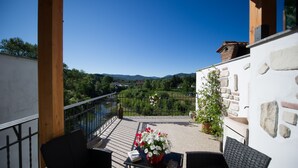 Un balcon donnant sur une vallée, un mur en pierre et une plante en pot.