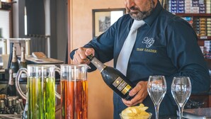 A bartender pouring a drink into a glass.