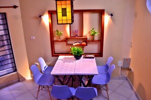 A dining area with a table, chairs, a potted plant, and shelves with decorative items. - Mia House Hanoi Central (Hanoi)