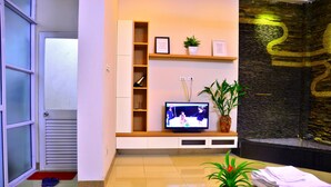Una sala de estar con televisor, planta y un mostrador de recepción.