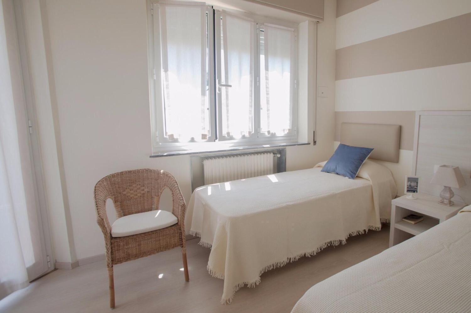 Une chambre à coucher avec un lit, une chaise, une table de chevet et une fenêtre.