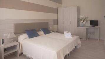 A bedroom with a bed, bedside tables, a desk, a TV, and a wardrobe.