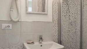A bathroom with a white sink, a mirror, and a shower area. - Locanda Kon Tiki (Alassio)