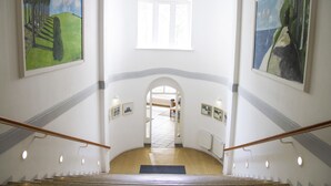 A staircase with a handrail, leading to a landing with a view of a room.
