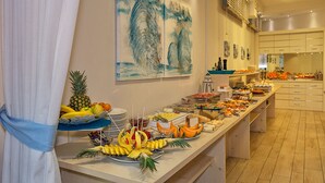 A buffet setup with various food items and a large abstract painting on the wall. - Hotel Central Park (Pietrasanta)