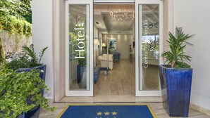 The entrance of Hotel Central Park Versilia Resort with a blue carpet and glass doors. - Hotel Central Park (Pietrasanta)