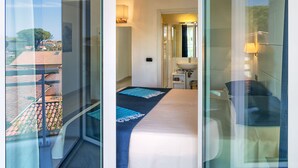 A modern hotel room with a balcony, a bed, a bathroom, and a view of the outside. - Hotel Central Park (Pietrasanta)