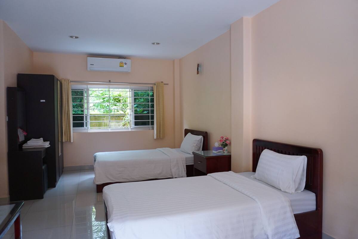 Habitación de hotel con dos camas, un escritorio, un armario y una ventana con cortinas.