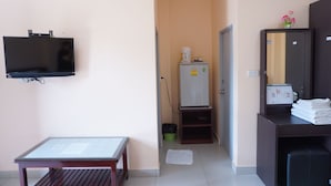 Une chambre d’hôtel équipée d’un téléviseur à écran plat fixé au mur, d’une petite table avec un menu, d’un meuble contenant des serviettes pliées et d’un distributeur d’eau.