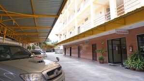 Un immeuble à plusieurs étages doté d’un parking couvert, d’un extincteur et de plantes en pot.