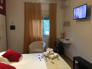 Una habitación de hotel con cama, escritorio, silla y televisor en la pared.