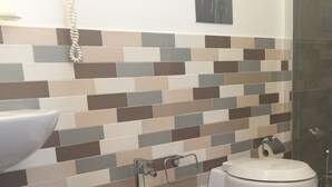 Un bany modern amb un respatller de rajoles, un lavabo, dos orinals i un vàter.