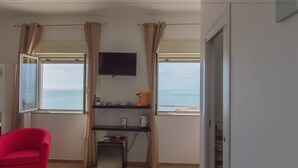Habitació amb televisió penjada a la paret, una taula petita amb un búl i una cadira vermella.