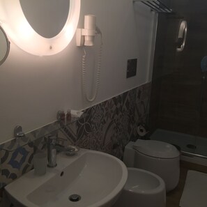Un baño con lavamanos, inodoro y espejo con luz.