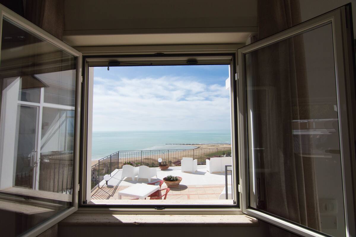 A balcony with a view of the beach and ocean.