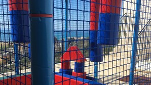 Zona de jocs infantil amb bressol de pilotes i elements per escalar.