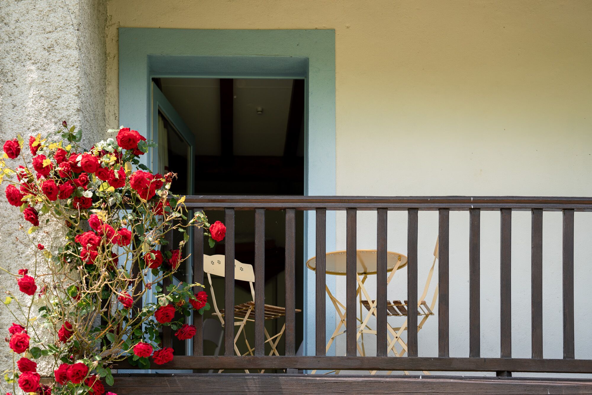 A balcony with a wooden railing, a table, and chairs.