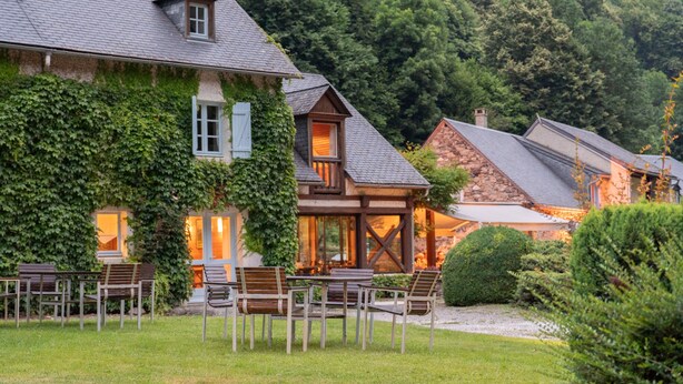Un chalet tradicional con fachada de piedra, contraventanas de madera y un balcón.