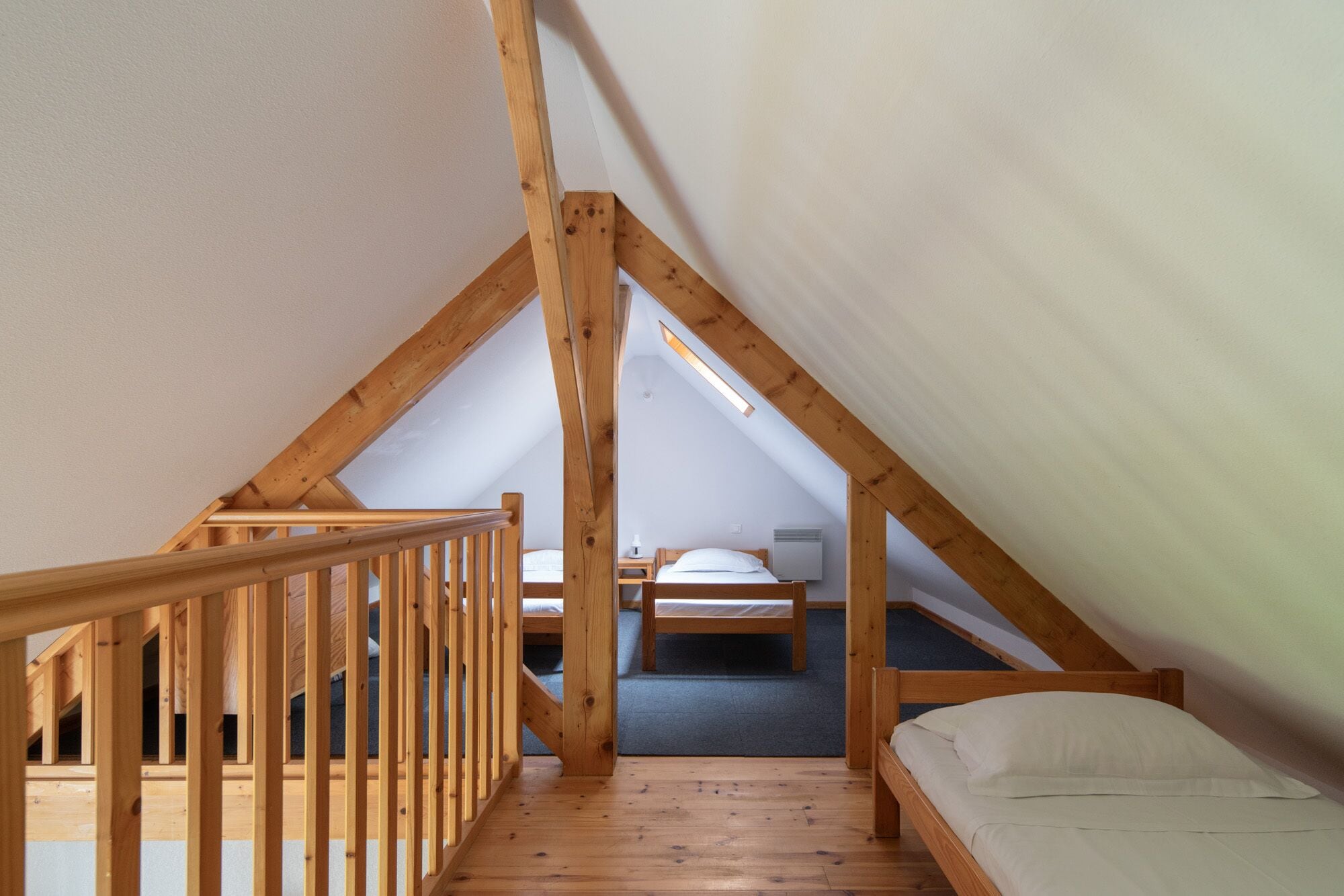 Ein kleines Schlafzimmer im Dachgeschoss mit Holzbalken, einer Holztreppe und zwei Betten.