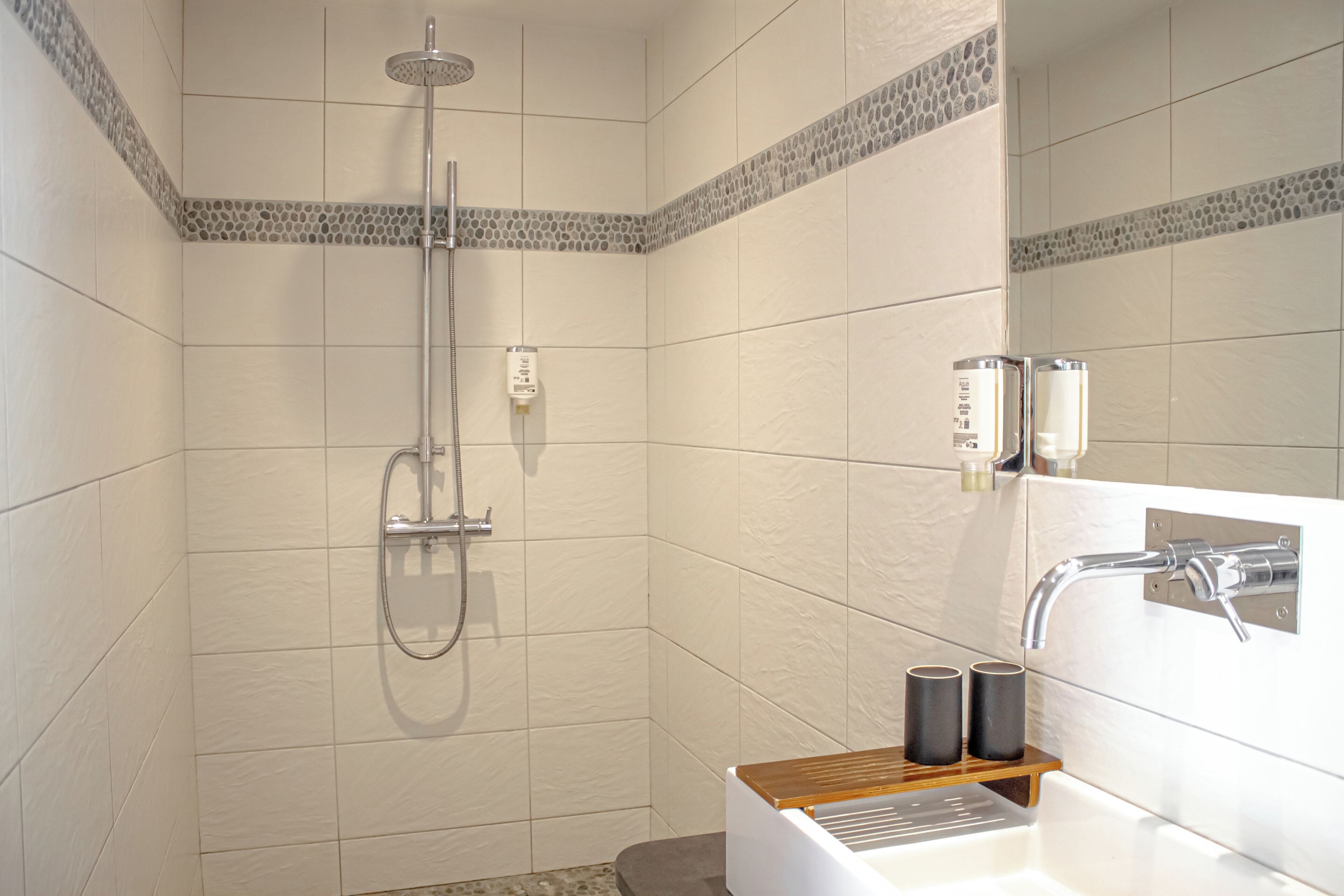 A modern bathroom with a shower, a sink, and a mirror.