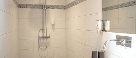 Un baño moderno con ducha, lavamanos y espejo.