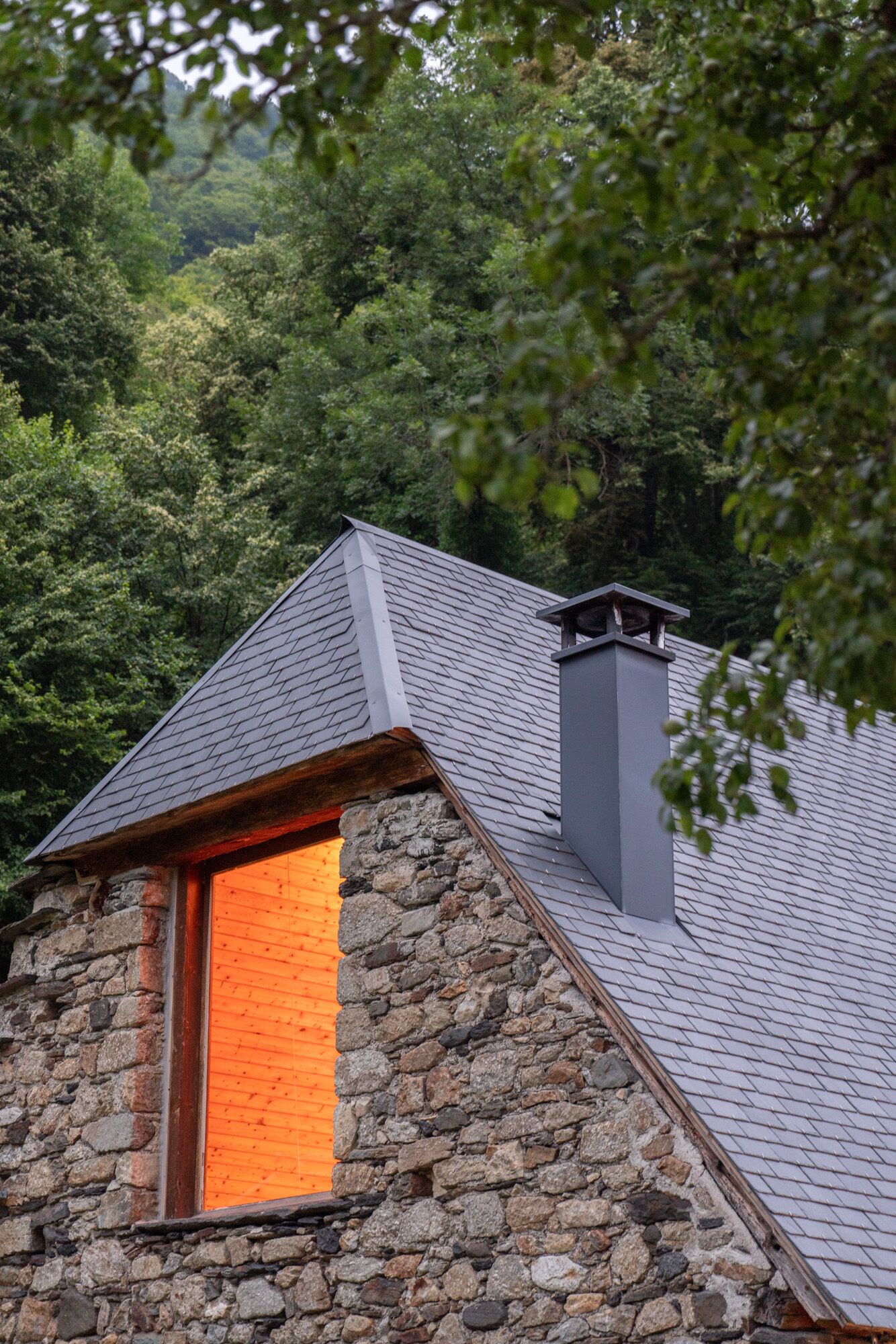 A stone building with a sloped roof and a chimney.