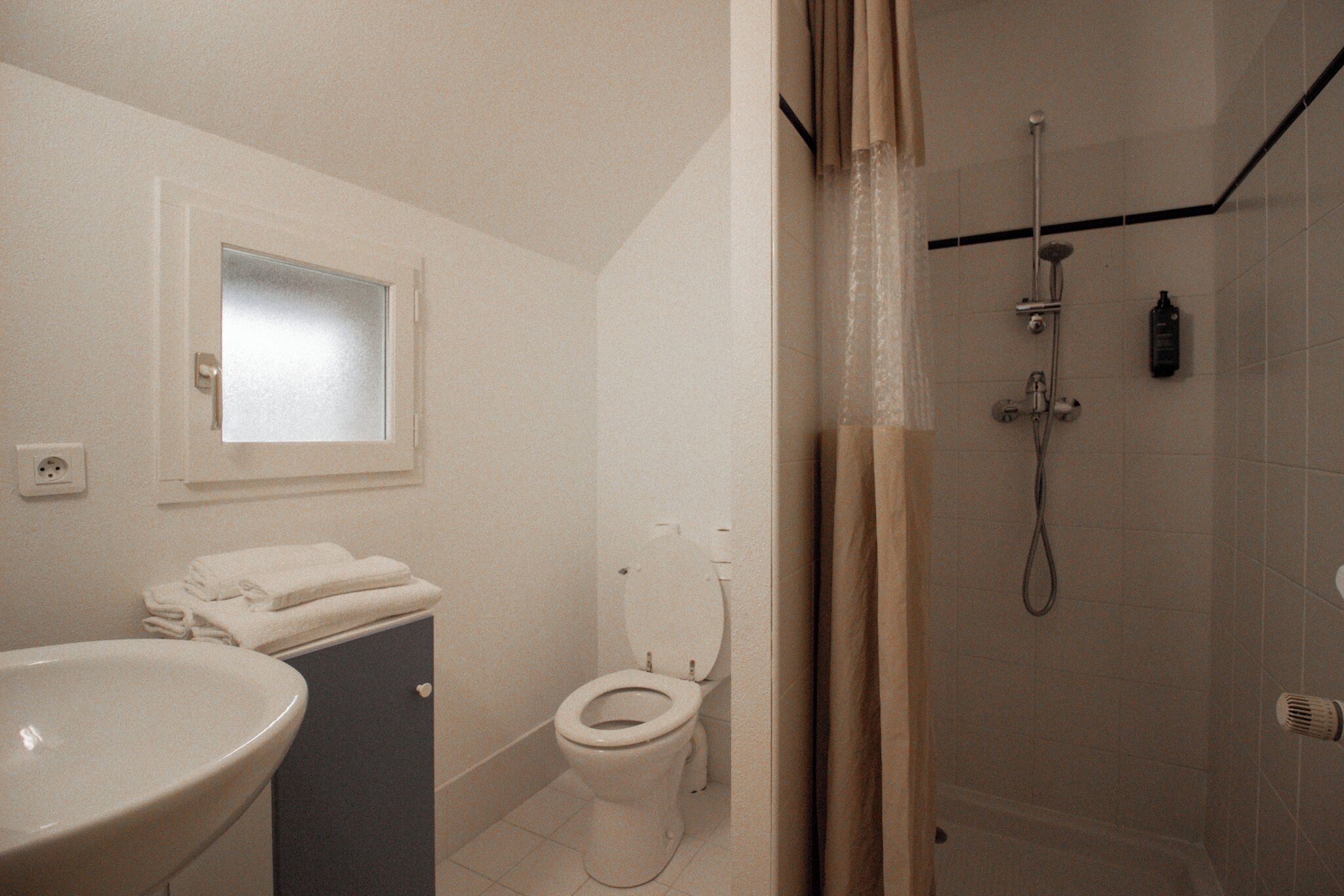 Un baño con lavamanos, inodoro y ducha.