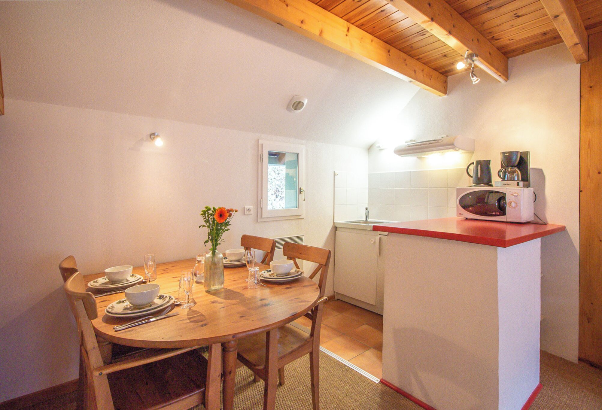Una cocina compacta con comedor, techo de madera y servicios básicos.