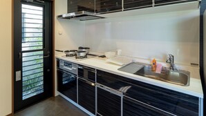 Eine moderne Küche mit eingebautem Herd, einer Spüle und einem Fenster mit Jalousien.