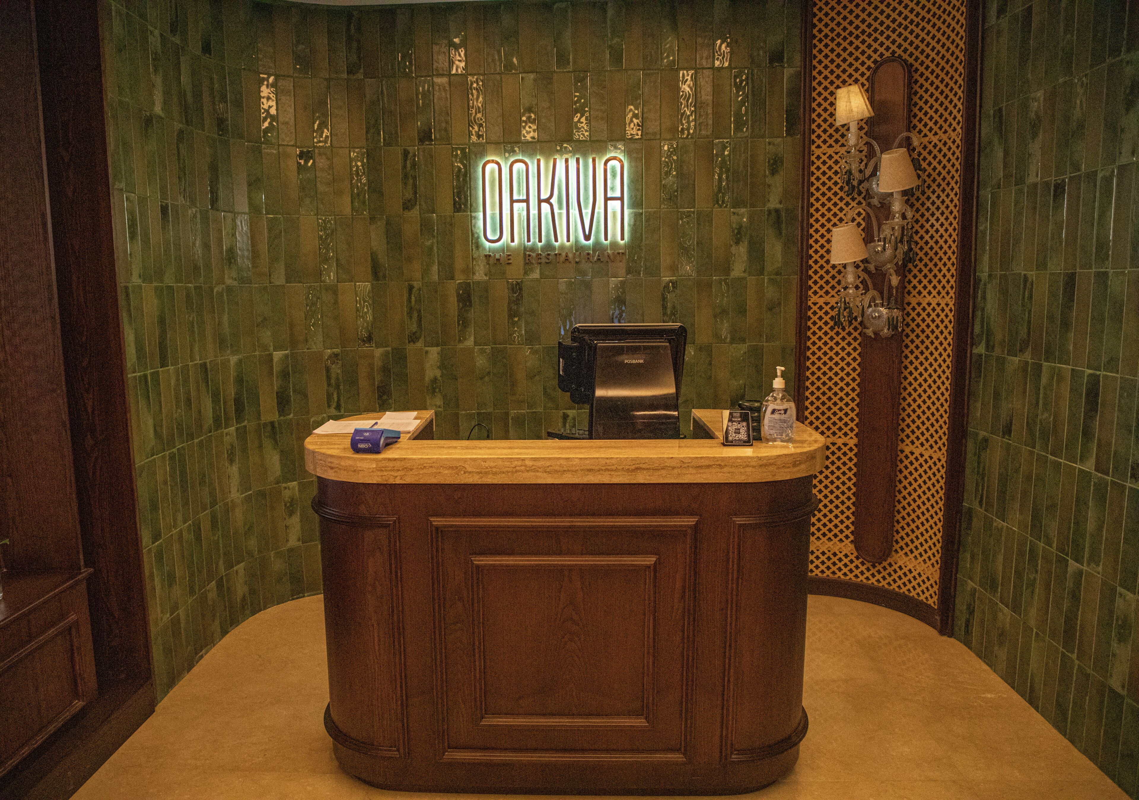 A reception desk with a sign above it, a mirror, and a wall with a patterned design.