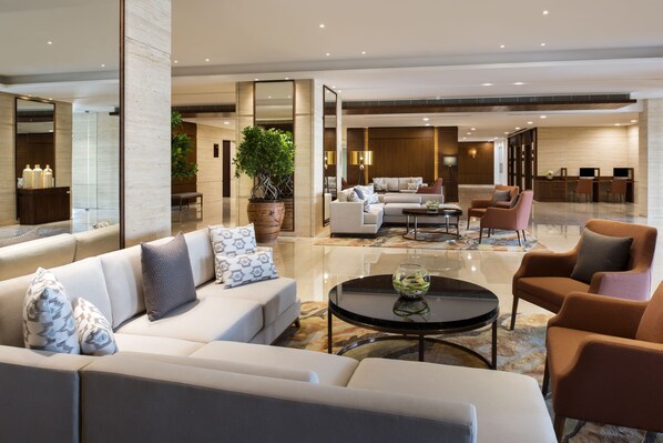 Una sala de estar moderna con un sofá, sillones, una mesita de centro y una planta en maceta.