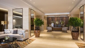 A spacious lobby with a reception desk, seating area, and large potted plants. - Fraser Suites Muscat (Muscat)