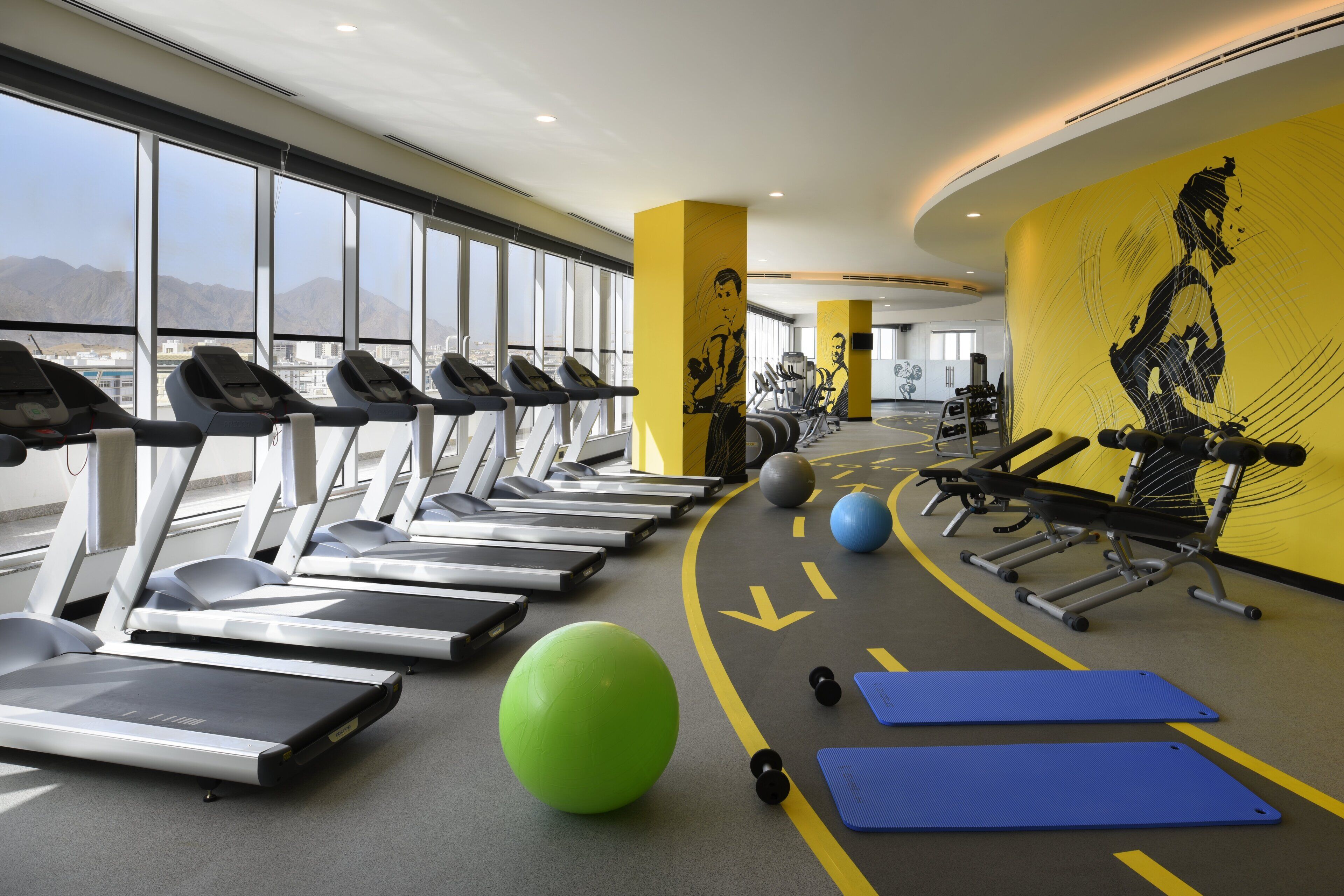 A gym with treadmills, exercise balls, and weights.