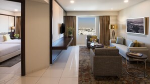 A modern hotel room with a bed, a sofa, a coffee table, and a TV. - Fraser Suites Muscat (Muscat)