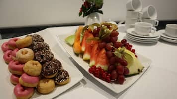 A breakfast buffet with donuts and fresh fruit.