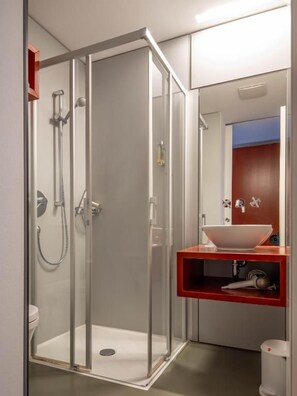 A modern bathroom with a glass-enclosed shower, a white sink, and a red vanity. - Evangelisches  Augustinerkloster Erfurt (Erfurt)