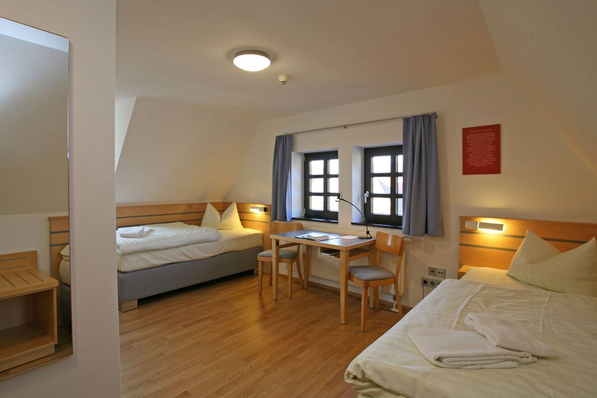 Ein Hotelzimmer mit zwei Betten, einem Schreibtisch und einem Stuhl.