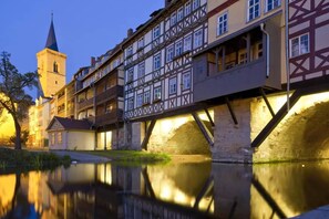 A historic European town with a prominent church tower and a bridge over a calm river. - Evangelisches  Augustinerkloster Erfurt (Erfurt)