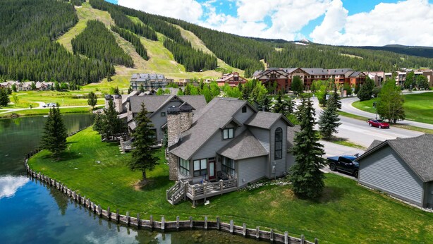 A lakeside lodge with a dock, surrounded by lush greenery and a mountain backdrop. - Private Mountain Town home Pet Friendly with Great Views - WD12 by Redawning (Copper Mountain)